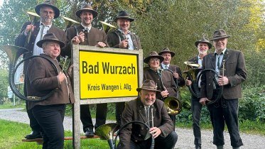 Jagdhornbl&auml;ser in traditioneller Tracht posiert an einem Ortsschild von Bad Wurzach &copy; Jagdhornbl&auml;ser