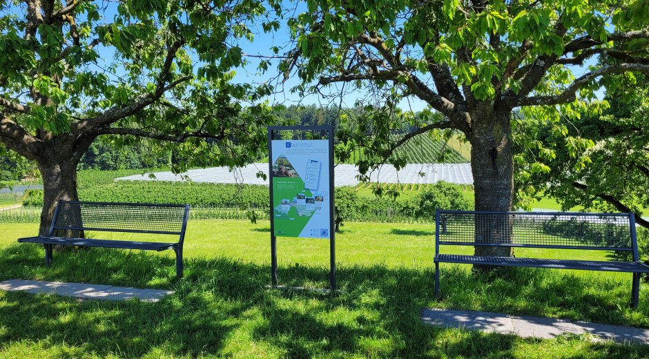 Tafel FacettenReich Genussstation neben zwei Sitzbänken Tafel FacettenReich Genussstation neben zwei Sitzbänken