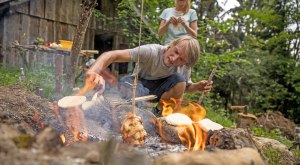 Ein Vater sitzt vor dem lodernden Lagerfeuer, im Hintergrund steht ein begeistertes Kind... &copy; Waldwelt Skywalk Allg&auml;u