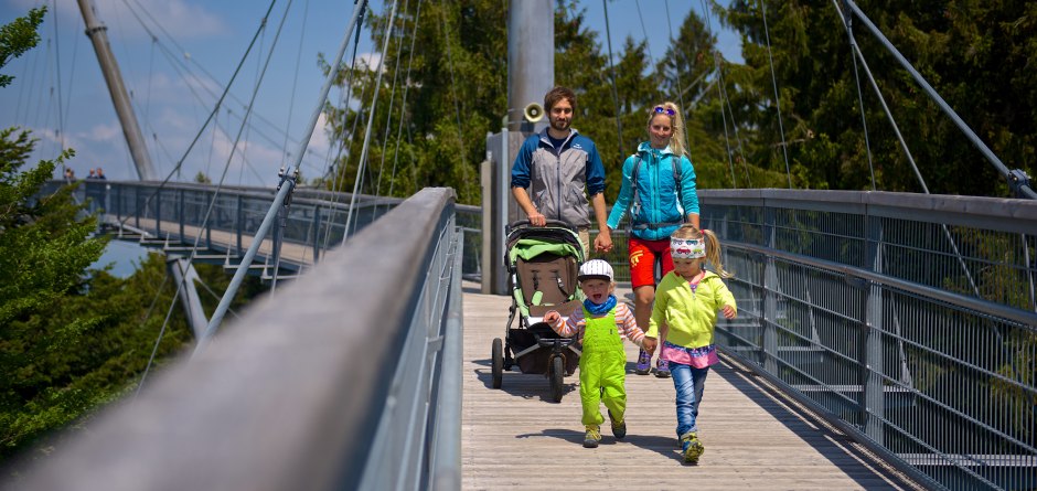 Eine Familie mit drei kleinen Kindern läuft fröhlich, bei strahlendem Sonnenschein, über den Skywalk... © Waldwelt Skywalk Allgäu Eine Familie mit drei kleinen Kindern läuft fröhlich, bei strahlendem Sonnenschein, über den Skywalk... © Waldwelt Skywalk Allgäu